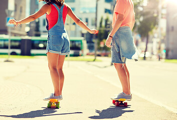 Image showing teenage couple riding skateboards on city street