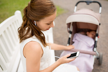 Image showing mother with smartphone, earphones and stroller