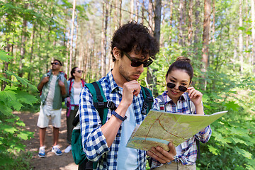 Image showing friends with map and backpacks hiking in forest