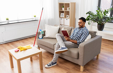 Image showing man reading book and resting after home cleaning