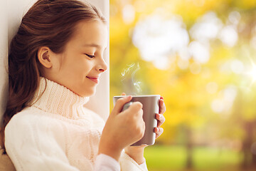 Image showing girl with tea mug sitting at home window in autumn