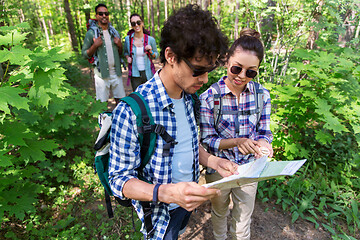 Image showing friends with map and backpacks hiking in forest