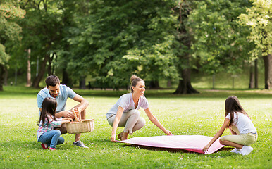 Image showing family laying down picnic blanket in summer park