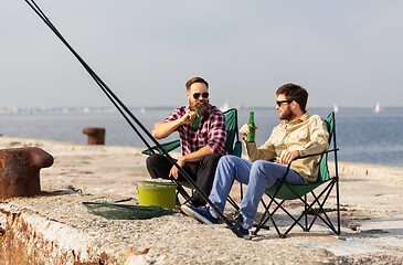 Image showing male friends fishing and drinking beer on pier