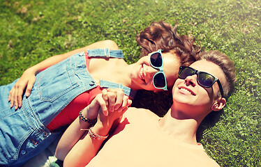 Image showing happy teenage couple lying on grass at summer