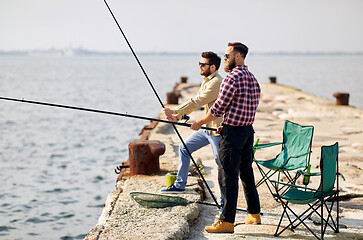 Image showing happy friends with fishing rods on pier