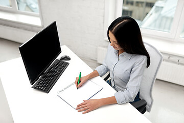 Image showing businesswoman writing to notebook at office