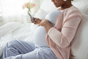 Image showing pregnant woman with smartphone in bed at home