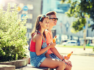 Image showing happy teenage couple eating hot dogs in city