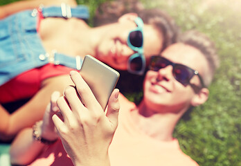 Image showing happy teenage couple smartphone lying on grass