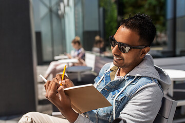 Image showing man with notebook and coffee at street cafe