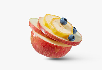 Image showing Fresh ripe natural apple with slices of banana and blueberries on a white background.