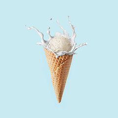 Image showing Fresh natural ice-cream in a corn with milk splash against pastel blue background.