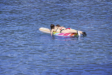 Image showing Two young girls swimming on air mattress in the sea