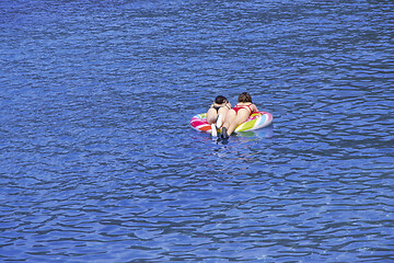 Image showing Two young girls swimming on air mattress in the sea