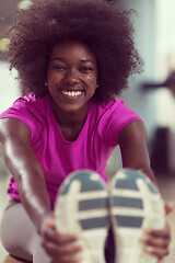 Image showing woman in a gym stretching and warming up before workout