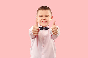 Image showing The happy teen boy standing and smiling against pink background.