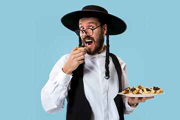 Image showing The young orthodox Jewish man with black hat with Hamantaschen cookies for Jewish festival of Purim