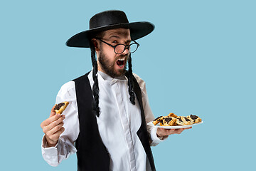 Image showing The young orthodox Jewish man with black hat with Hamantaschen cookies for Jewish festival of Purim