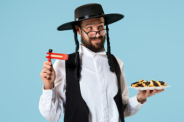 Image showing The young orthodox Jewish man with black hat with Hamantaschen cookies for Jewish festival of Purim