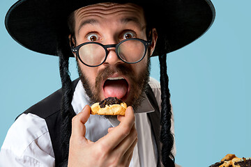 Image showing The young orthodox Jewish man with black hat with Hamantaschen cookies for Jewish festival of Purim