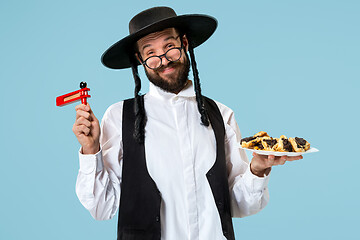 Image showing The young orthodox Jewish man with black hat with Hamantaschen cookies for Jewish festival of Purim