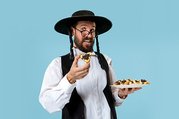 Image showing The young orthodox Jewish man with black hat with Hamantaschen cookies for Jewish festival of Purim