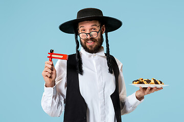 Image showing The young orthodox Jewish man with black hat with Hamantaschen cookies for Jewish festival of Purim