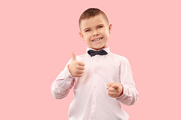 Image showing The happy teen boy standing and smiling against pink background.