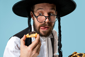 Image showing The young orthodox Jewish man with black hat with Hamantaschen cookies for Jewish festival of Purim