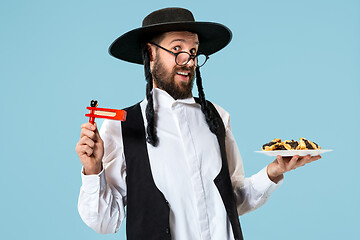 Image showing The young orthodox Jewish man with black hat with Hamantaschen cookies for Jewish festival of Purim