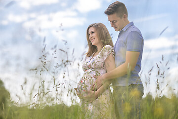 Image showing Young happy pregnant couple hugging in nature.