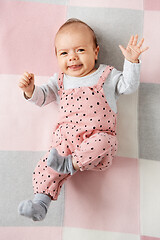 Image showing sweet baby girl in pink suit lying on blanket