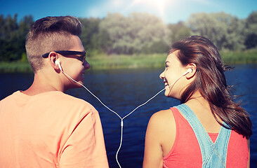 Image showing happy teenage couple with earphones on river berth