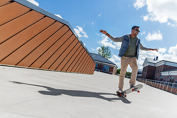 Image showing indian man doing trick on skateboard on roof top