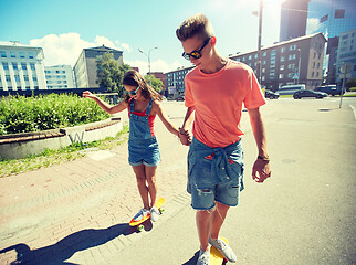 Image showing teenage couple riding skateboards on city street