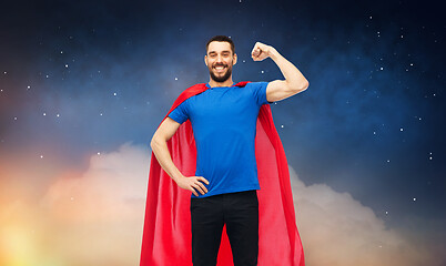 Image showing happy man in red superhero cape over night sky