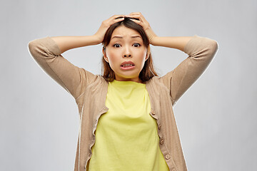 Image showing terrified asian woman holding to her head