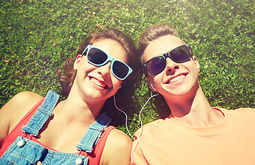 Image showing happy teenage couple with earphones lying on grass