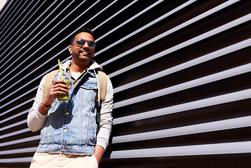 Image showing man with backpack drinking smoothie on street