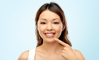 Image showing happy smiling young asian woman touching her face