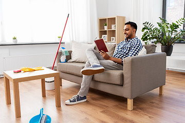 Image showing man reading book and resting after home cleaning