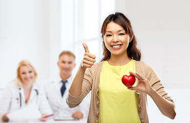 Image showing happy asian woman with red heart showing thumbs up