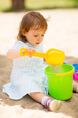 Image showing little baby girl plays with toys in sandbox