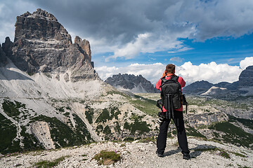 Image showing Nature photographer tourist with camera shoots while standing It