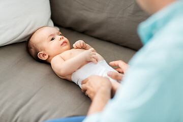 Image showing middle aged father changing baby\'s diaper at home