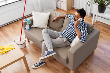 Image showing man calling on smartphone after cleaning home