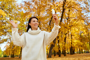 Image showing woman taking selfie with smartphone at autumn park