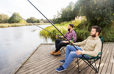 Image showing male friends fishing and drinking beer on lake