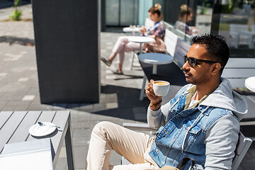 Image showing indian man drinking coffee at city street cafe